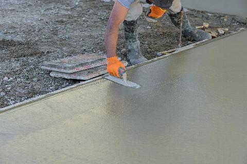 Man smoothing out cement foundation